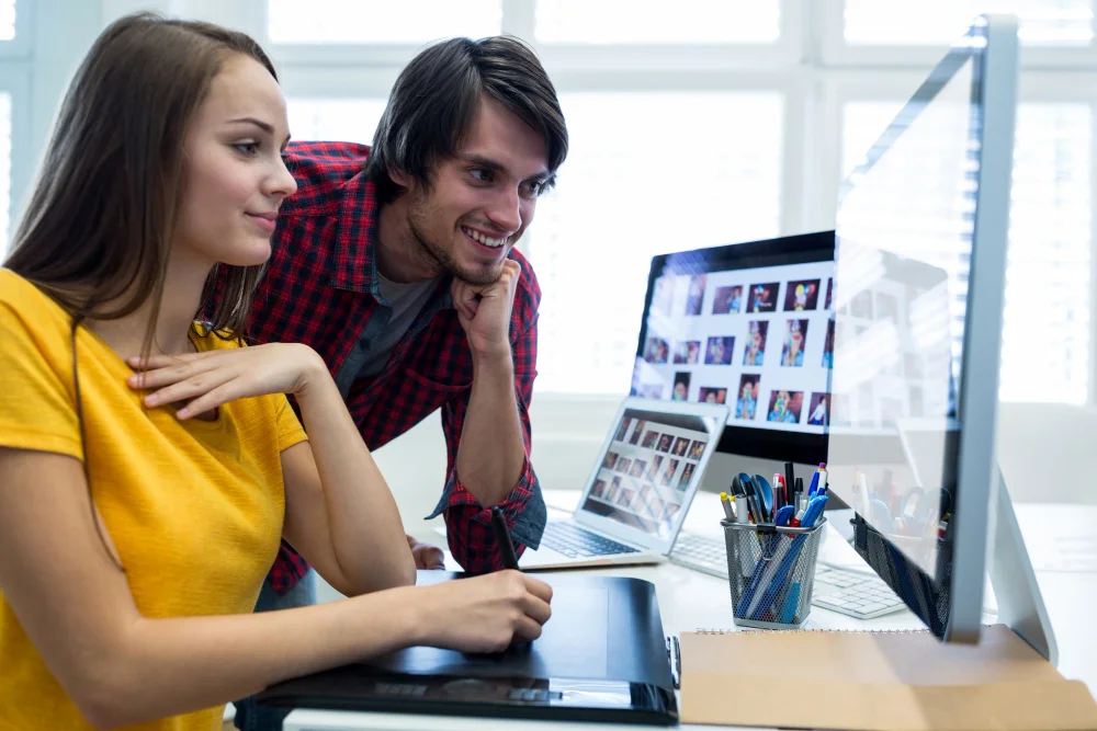 Dos personas trabajando juntas frente al computador en el diseño de una página web